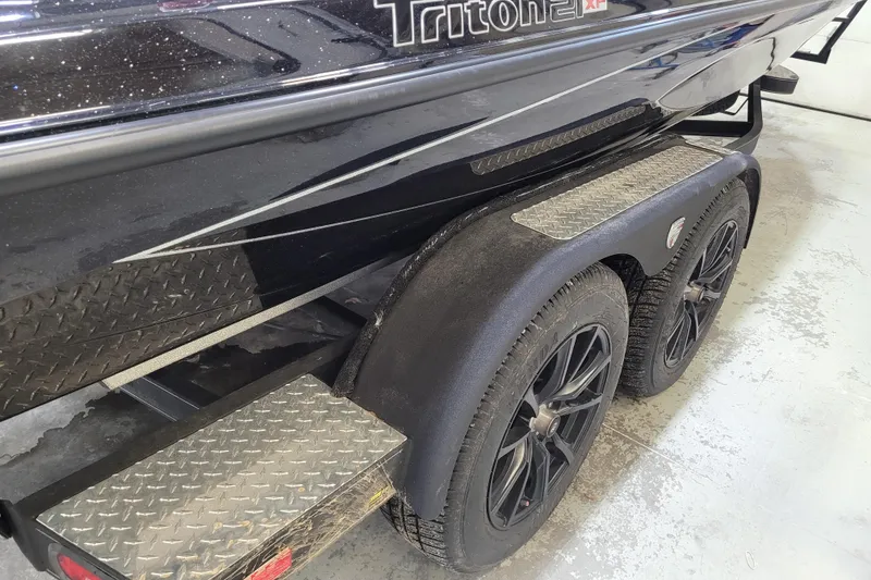 Slide: The Image of 2025 Triton 21XP boat trailer with dual black wheels and diamond plate steps. - 50