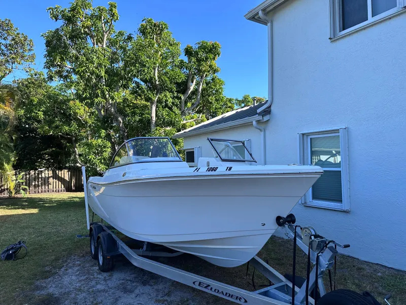 The Image of 2022 Cobia 220 Dual Console boat on trailer beside house. - 0