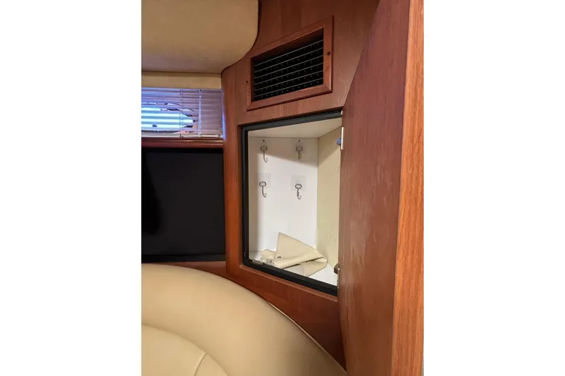 Slide: The Image of Interior of 2000 Cruisers 3870 yacht showing wooden cabinet with hooks and folded fabric. - 52