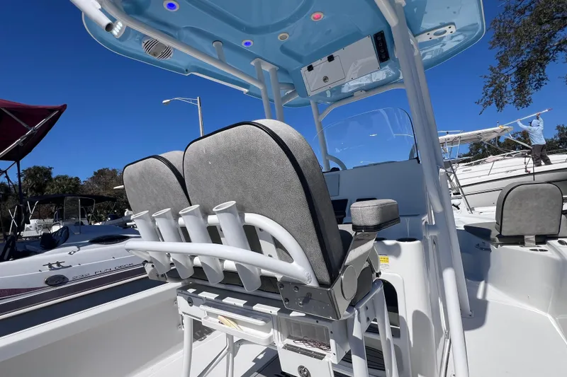 Slide: The Image of 2023 Sea Pro 248 Bay boat interior with seating and rod holders under a clear blue sky. - 20