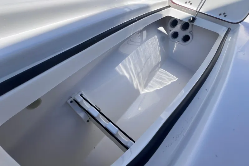 Slide: The Image of 2023 Sea Pro 248 Bay boat storage compartment with cup holders and open lid. - 41