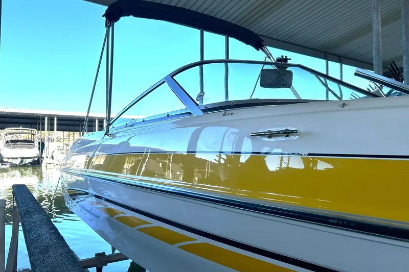 Slide: The Image of 2007 Glastron GT 205 boat with yellow stripe, docked under a covered marina. - 10