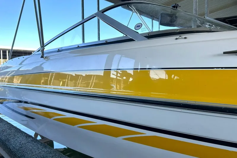 Slide: The Image of 2007 Glastron GT 205 boat with yellow and white exterior, docked in a marina. - 11