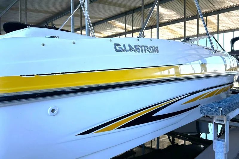 Slide: The Image of 2007 Glastron GT 205 boat with yellow and black accents in a covered dock. - 12
