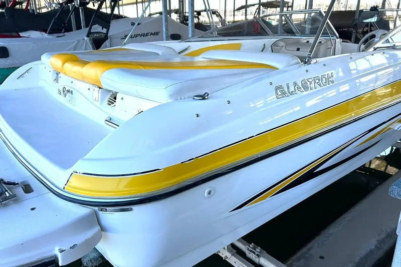 Slide: The Image of 2007 Glastron GT 205 boat with yellow accents, docked in a marina. - 13