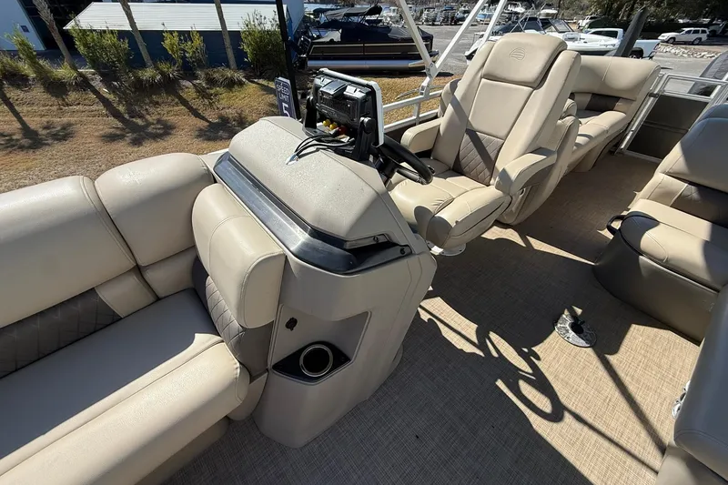 Slide: The Image of 2024 Sun Tracker Party Barge 22 DLX interior with beige seating and steering console. - 12