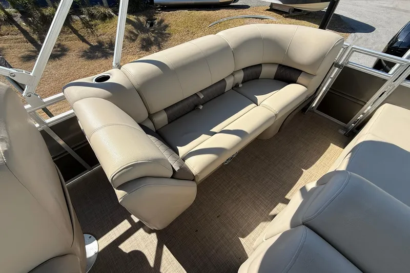 Slide: The Image of 2024 Sun Tracker Party Barge 22 DLX interior with beige seating and cup holder. - 19