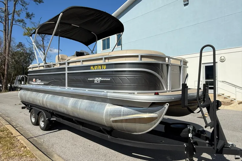 Slide: The Image of 2024 Sun Tracker Party Barge 22 DLX pontoon boat on trailer, parked outdoors. - 4