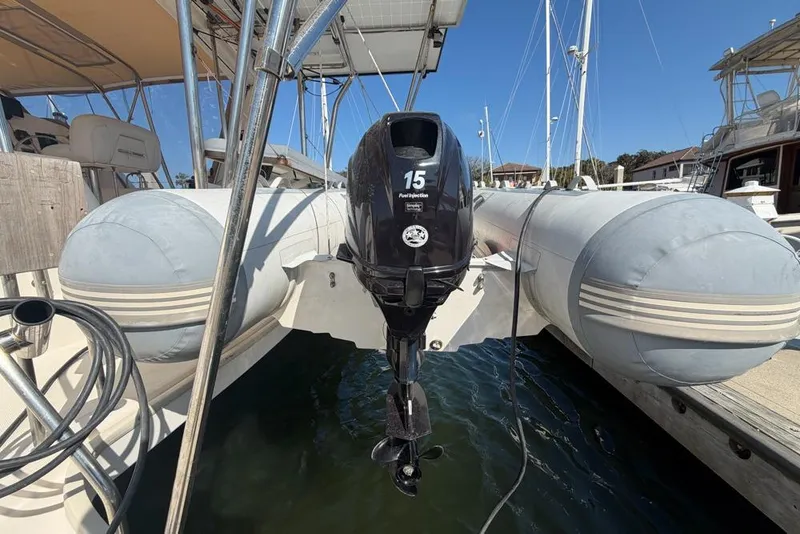 Slide: The Image of Inflatable boat with outboard motor docked beside a Leopard 38 catamaran, 2000 model. - 122