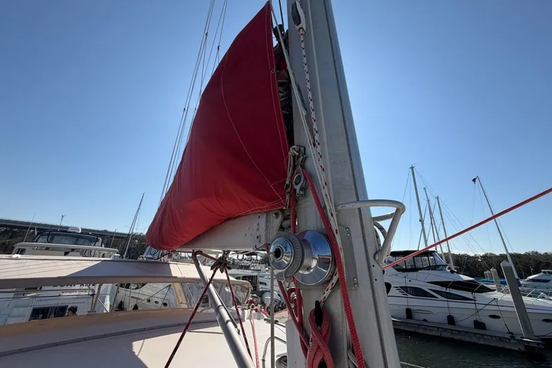 Slide: The Image of Sailboat with red sail cover, Leopard 38 model, docked in marina under clear sky. - 139