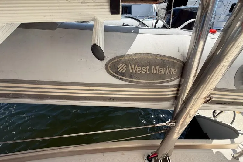 Slide: The Image of Inflatable boat with "West Marine" logo, docked near a Leopard 38 catamaran. - 183