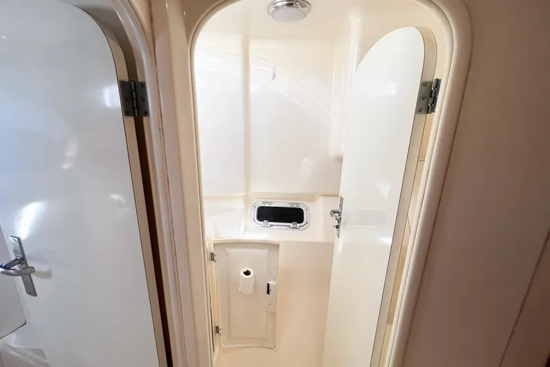 Slide: The Image of Compact bathroom in a 2000 Leopard 38 yacht, featuring white interior and small window. - 61