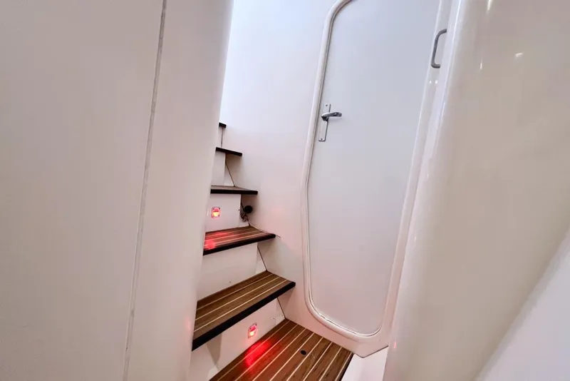 Slide: The Image of Staircase with red lights leading to a door inside a 2000 Leopard 38 yacht. - 66