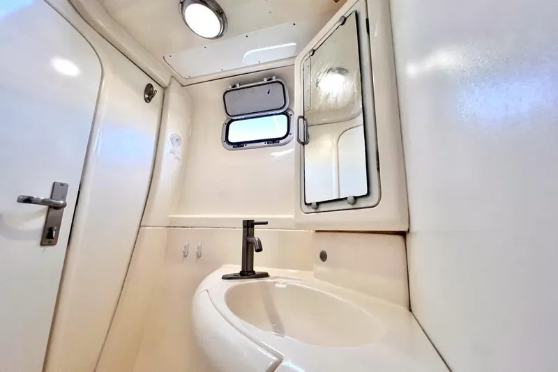 Slide: The Image of Compact bathroom in 2000 Leopard 38 yacht with sink, mirror, and porthole window. - 94