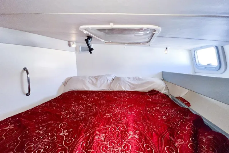Slide: The Image of Cozy cabin interior of 2000 Leopard 38 with red patterned bedding and porthole window. - 99