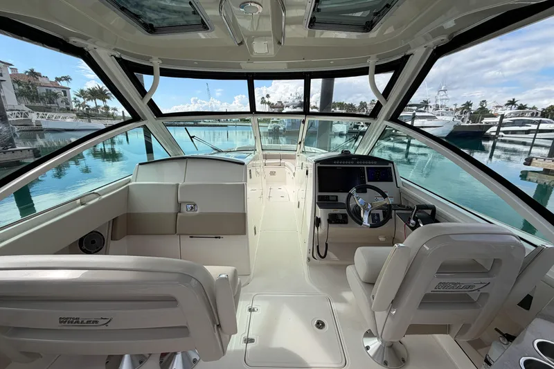 Slide: The Image of 2022 Boston Whaler 320 Vantage boat interior with helm, seats, and marina view. - 26