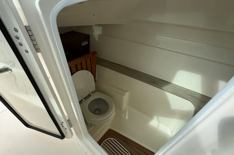 Slide: The Image of 2022 Boston Whaler 320 Vantage boat interior bathroom with toilet and wooden accents. - 33