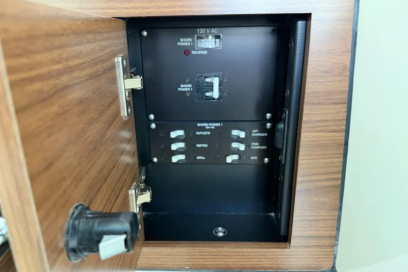 Slide: The Image of Electrical panel inside 2022 Boston Whaler 320 Vantage boat, featuring shore power controls. - 36