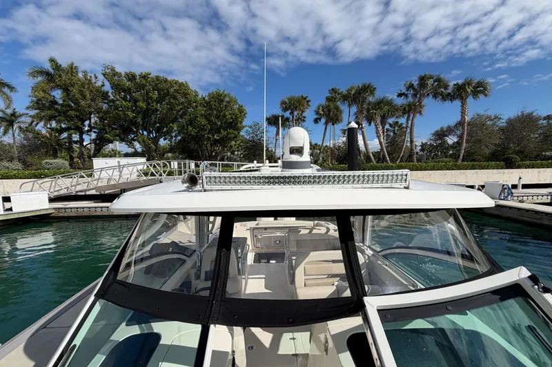 Slide: The Image of 2022 Boston Whaler 320 Vantage boat docked, surrounded by palm trees and clear skies. - 44