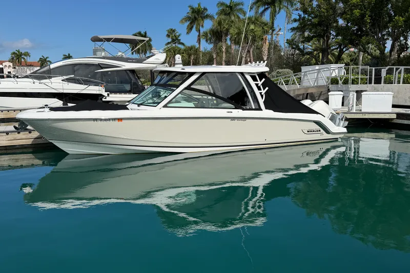 Slide: The Image of 2022 Boston Whaler 320 Vantage boat docked in a marina with palm trees. - 49