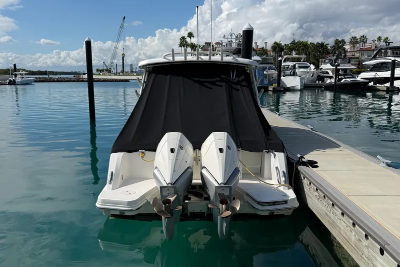 Slide: The Image of 2022 Boston Whaler 320 Vantage docked with twin engines, covered in black tarp. - 51