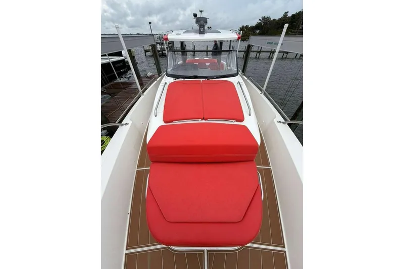 Slide: The Image of 2021 Nimbus T-11 boat with red cushions, docked by the water. - 7