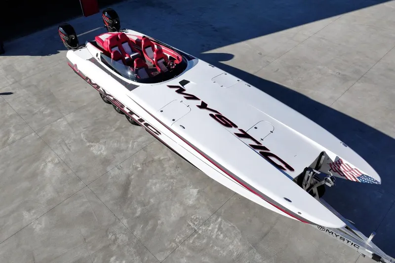 Slide: The Image of 2019 Mystic Powerboats C3800, sleek white design with red seating, aerial view. - 9