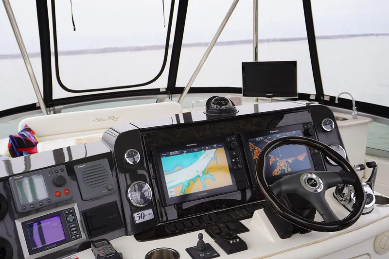 Slide: The Image of 2009 Sea Ray 47 Sedan Bridge helm with navigation screens and steering wheel. - 16