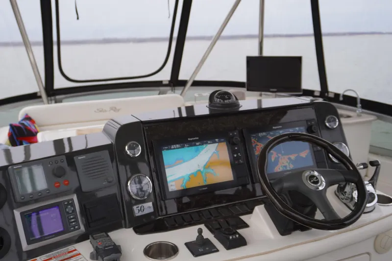 Slide: The Image of 2009 Sea Ray 47 Sedan Bridge helm with navigation screens and steering wheel. - 17