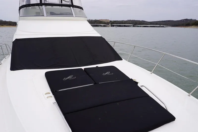 Slide: The Image of 2009 Sea Ray 47 Sedan Bridge yacht with black sun pads on deck, docked on calm water. - 24
