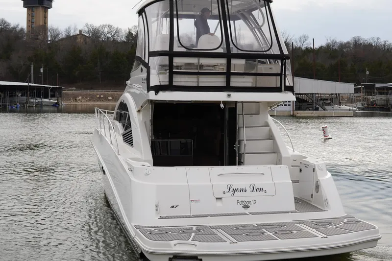Slide: The Image of 2009 Sea Ray 47 Sedan Bridge yacht on water, rear view, named "Lyons Den." - 3