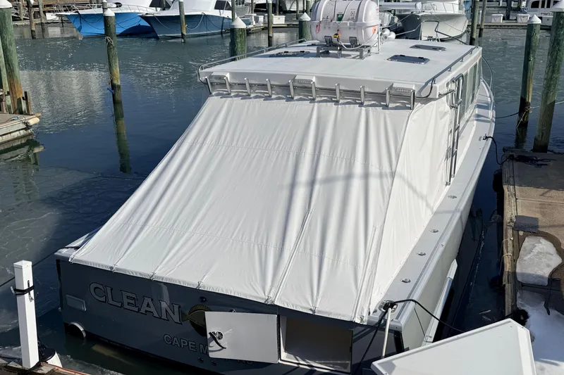 Slide: The Image of 2025 Wesmac 42 boat docked in a marina, featuring a sleek design and covered deck. - 2
