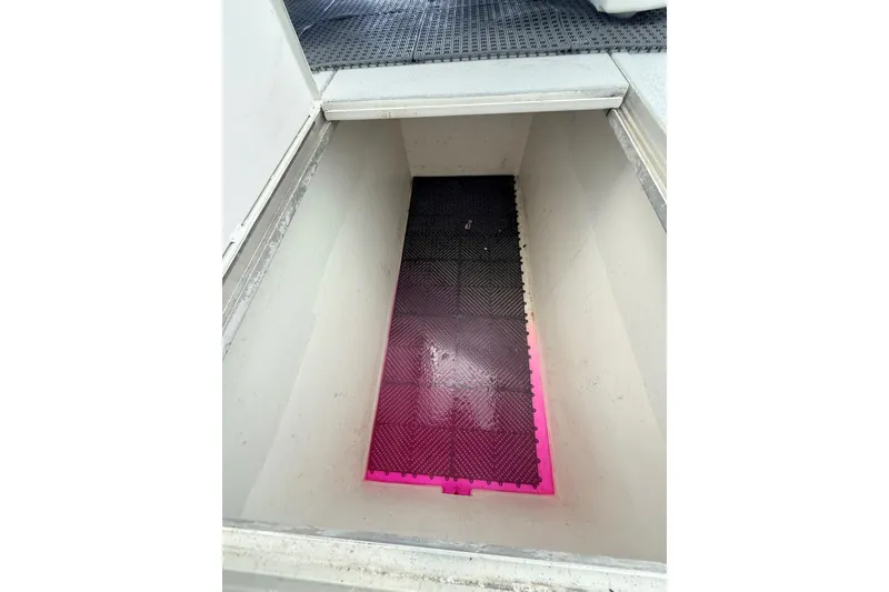 Slide: The Image of Open storage compartment on 2025 Wesmac 42 boat with pink and black flooring. - 68