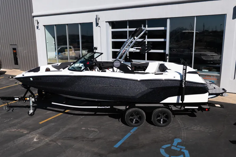 Slide: The Image of 2023 MasterCraft NXT22 boat on trailer, parked outside a building. - 5