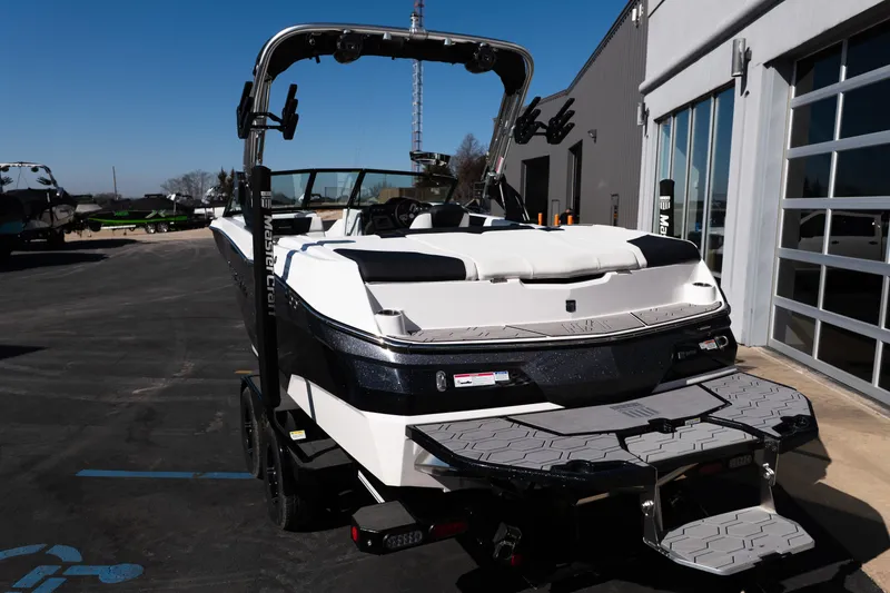 Slide: The Image of 2023 MasterCraft NXT22 boat parked outside a modern building on a sunny day. - 7