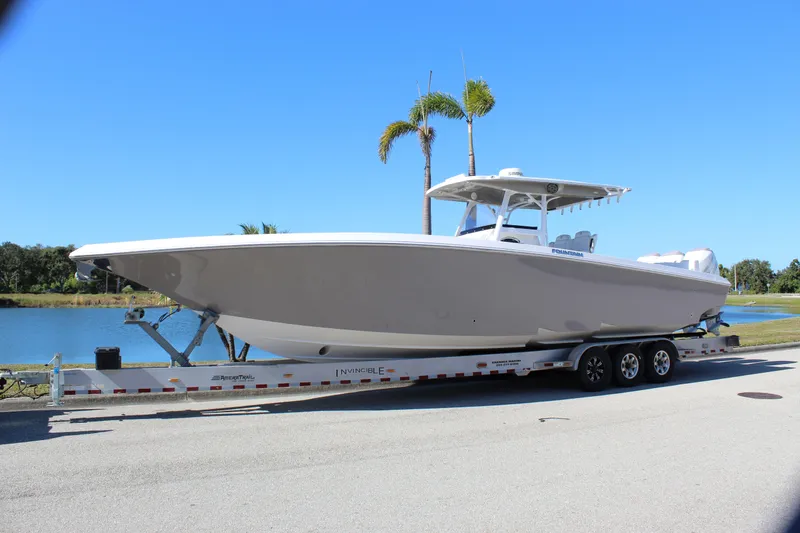 Slide: The Image of 2018 Fountain 38 CC Tournament Edition boat on trailer by a lake. - 10