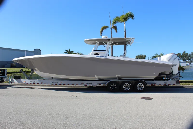 Slide: The Image of 2018 Fountain 38 CC Tournament Edition boat on trailer, parked near water. - 2