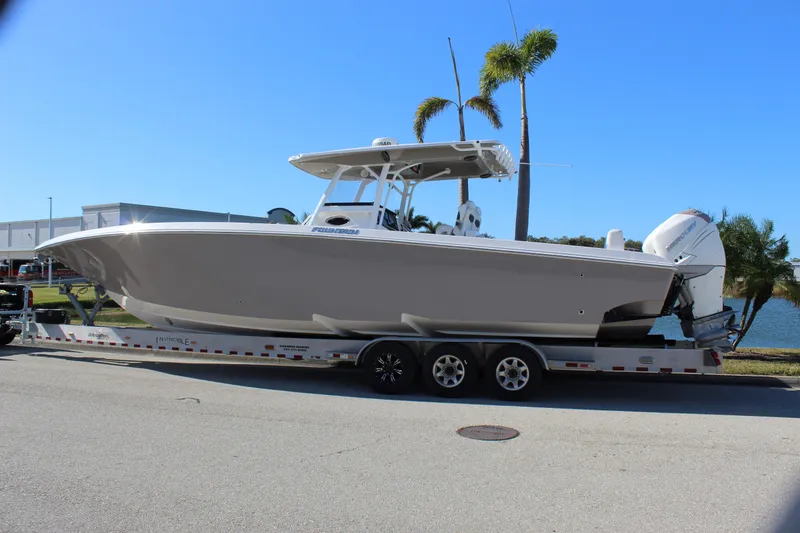 Slide: The Image of 2018 Fountain 38 CC Tournament Edition boat on trailer, parked near palm trees. - 3