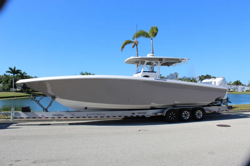 Slide: The Image of 2018 Fountain 38 CC Tournament Edition boat on trailer, parked near waterway. - 9