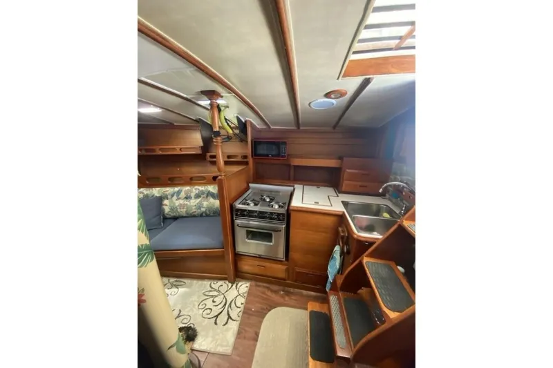 Slide: The Image of 1977 Ericson 36 C yacht interior with kitchen, seating, and wooden cabinetry. - 10