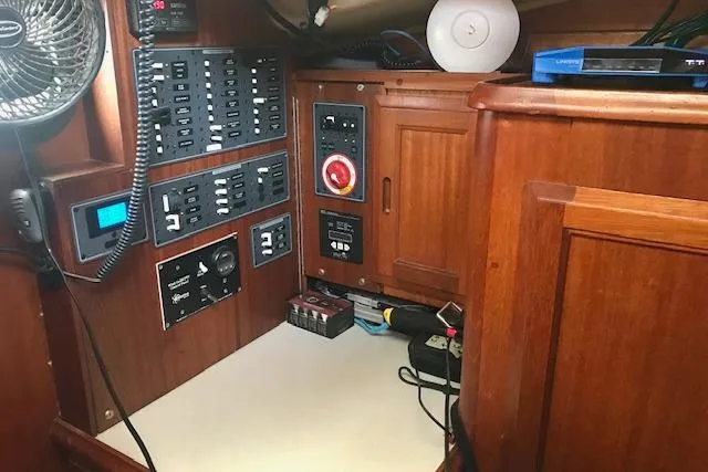 Slide: The Image of Electrical panel inside a 1977 Ericson 36 C sailboat, featuring wooden cabinetry and control switches. - 13