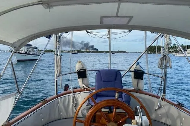 Slide: The Image of Cockpit view from 1977 Ericson 36 C sailboat, overlooking calm waters and distant smoke. - 17