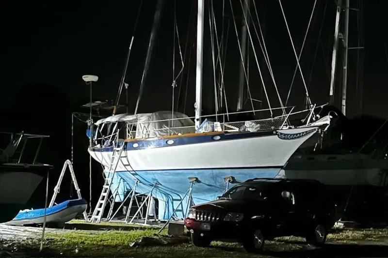 Slide: The Image of 1977 Ericson 36 C sailboat on land at night, with a car nearby. - 27