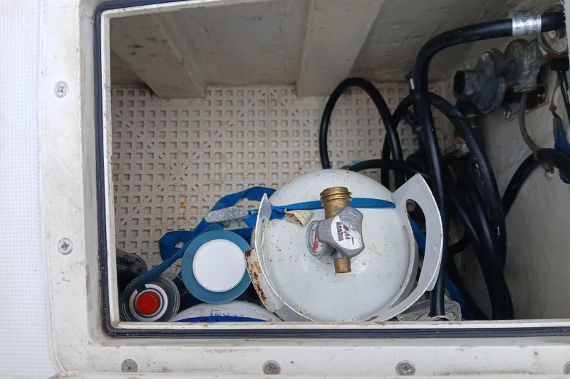 Slide: The Image of Storage compartment with propane tank and hoses on a 1977 Ericson 36 C sailboat. - 53