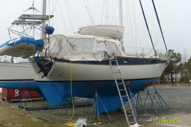 Slide: The Image of 1977 Ericson 36 C sailboat on stands, with a dinghy attached, in a boatyard. - 64