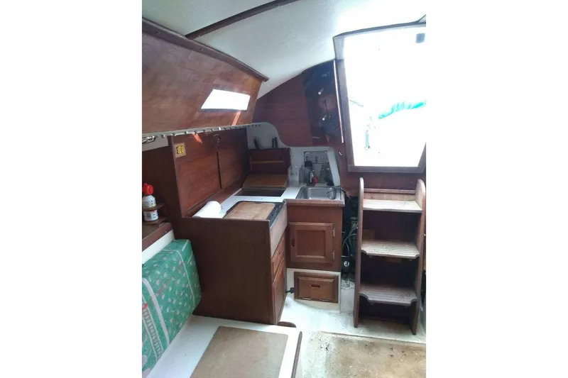 Slide: The Image of Interior of a 1975 WDS Santana sailboat with wooden cabinetry and compact kitchen area. - 12