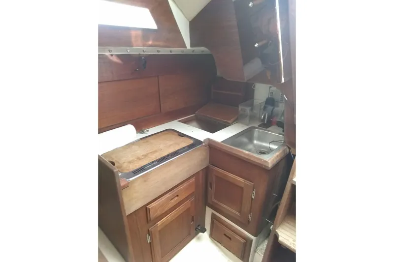 Slide: The Image of 1975 WDS Santana boat interior with wooden cabinetry and compact kitchen area. - 14