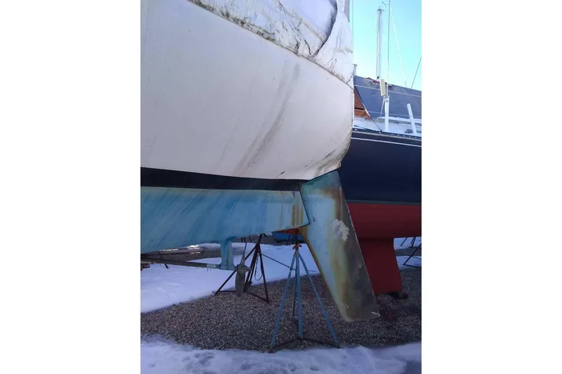 Slide: The Image of 1975 WDS Santana sailboat on stands, showing hull and rudder in a boatyard. - 6