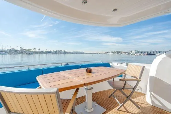 Slide: The Image of Sunseeker Manhattan 60 yacht deck with wooden table and chairs, overlooking serene waters. - 3