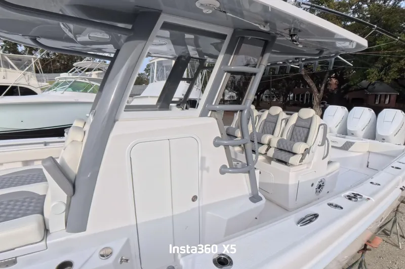 Slide: The Image of 2025 Invincible 39 Open Fisherman boat on dry land, surrounded by trees. - 1
